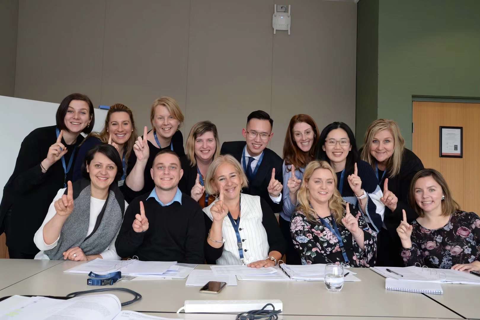 A group gathers on one side of a conference room table around CASE President and CEO Sue Cunningham. Everyone holds up their fingers in a #1 position.