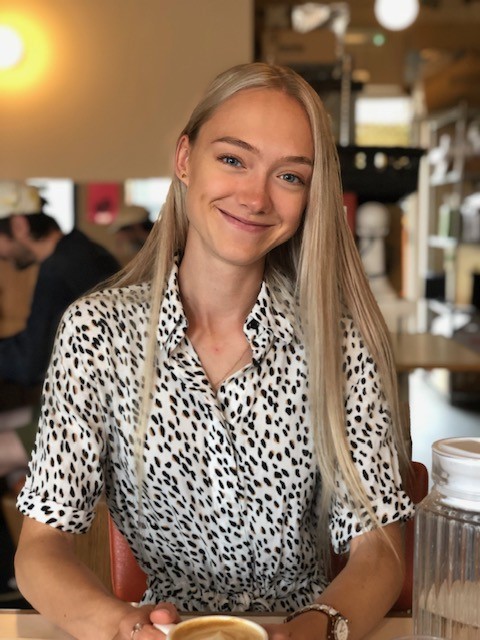 Headshot of Georgia Willmot, a woman with long blond hair, wearing a black and white patterned blouse.