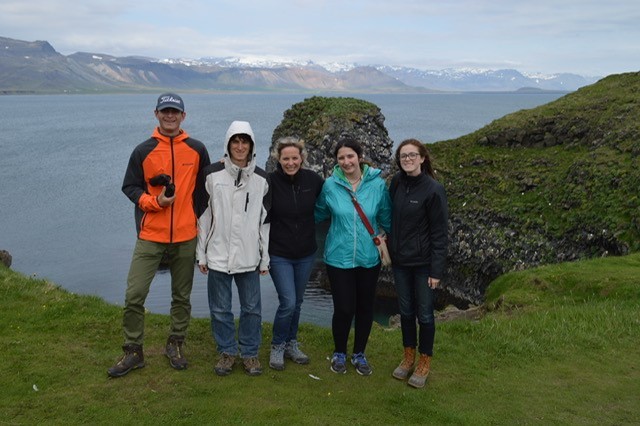 On a cliffside in Iceland, Meg Natter stands center, with two of her community students on either side.