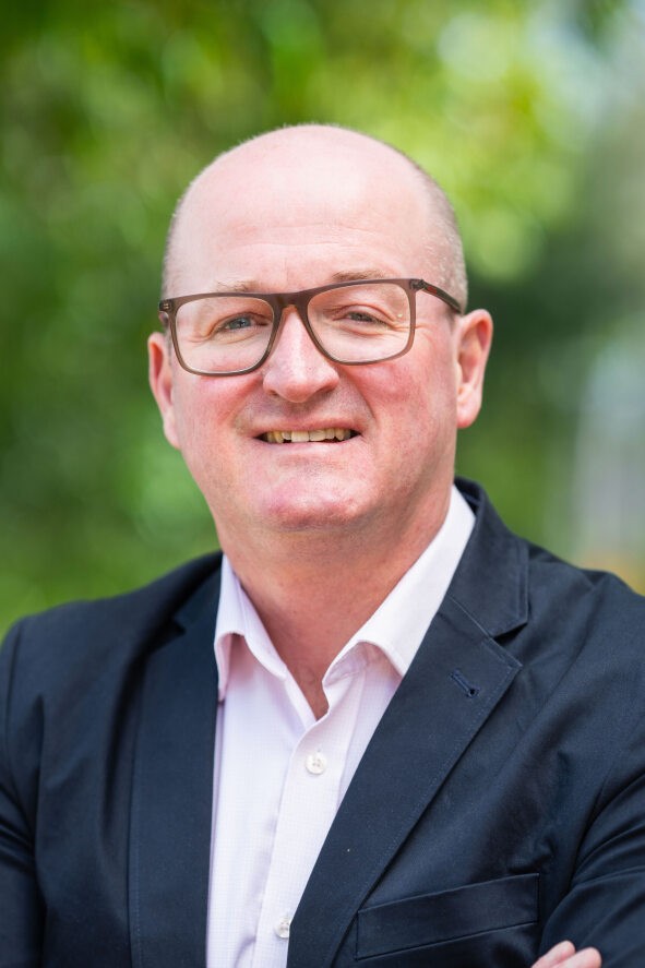 Marcus Ward headshot, a man wearing glasses, a button down, and a navy blazer.