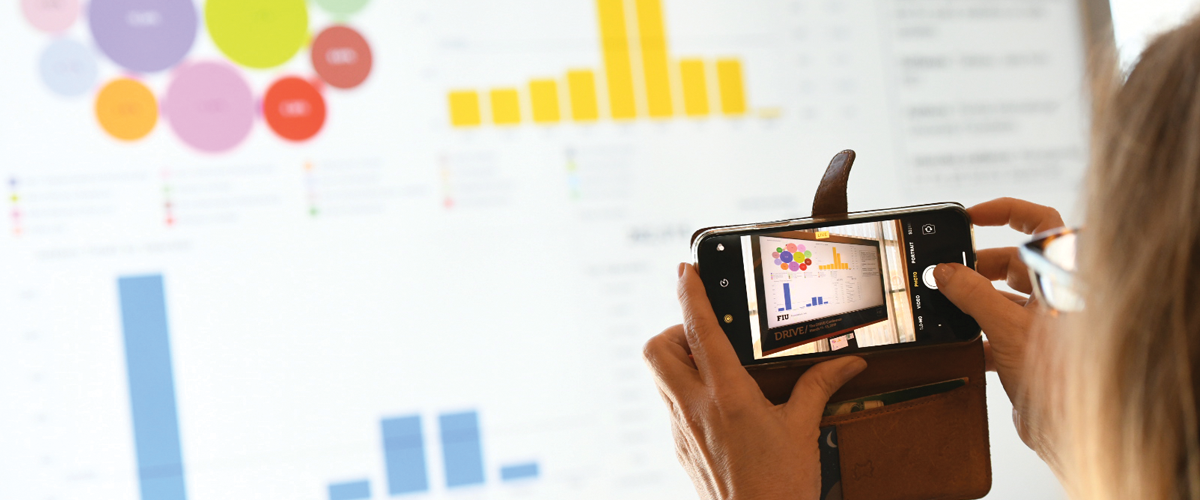 Close up of someone using a phone to take a photo of a screen displaying diagrams of CASE Insights data.