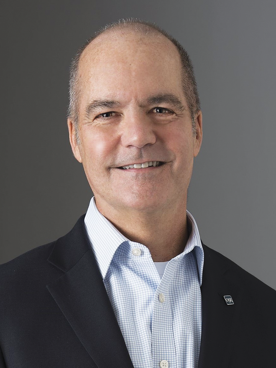 Headshot of Brett Chambers, wearing a button down, blazer, and CASE lapel pin.