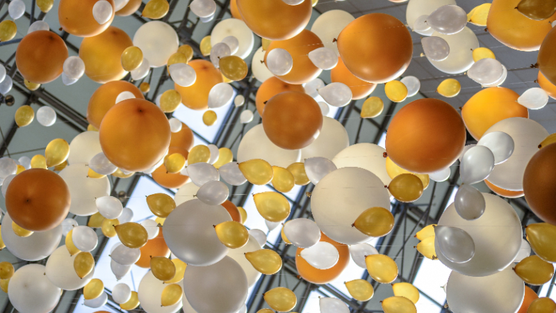 Multiple gold, orange, silver and white balloons of varied sizes.